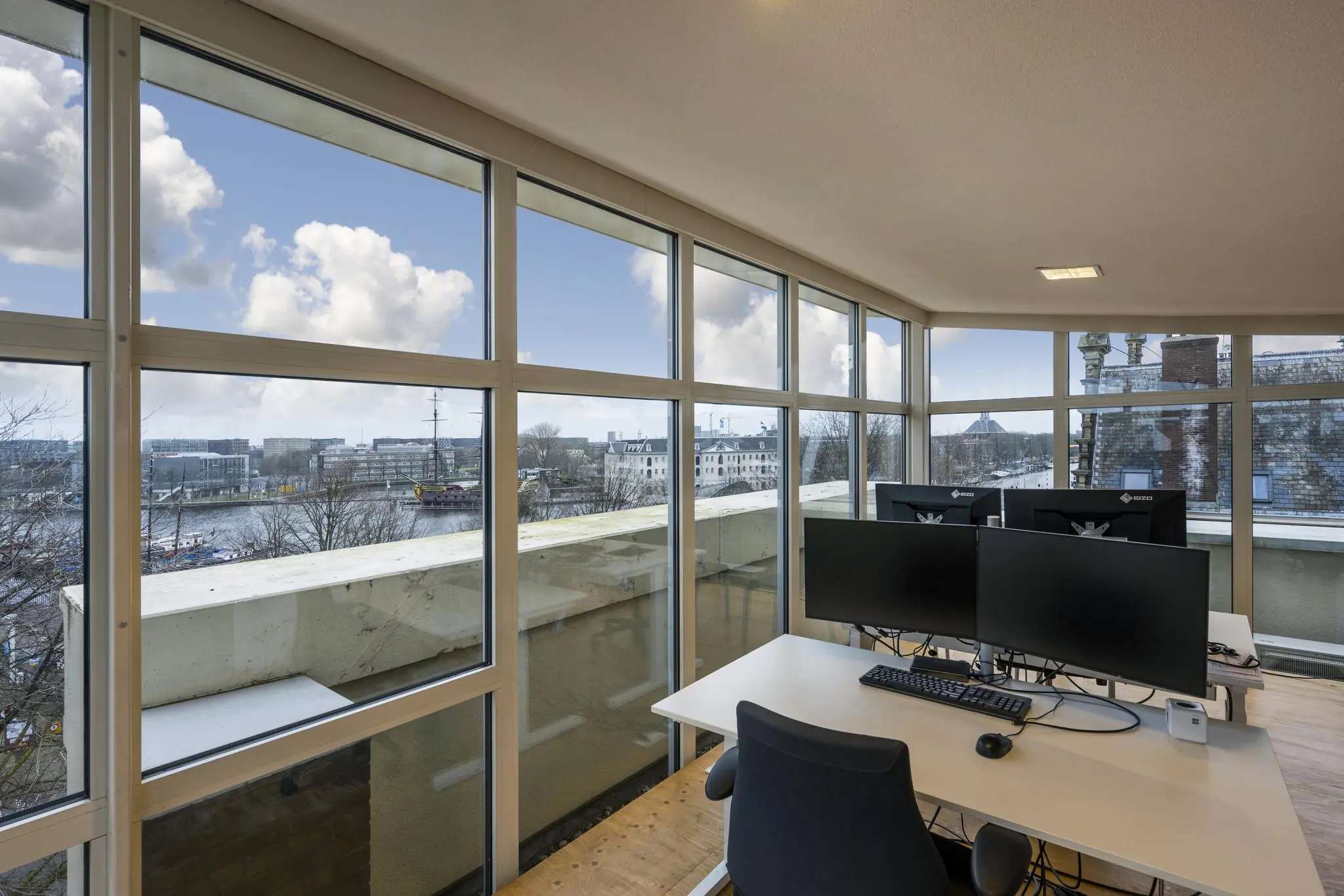 Modern kantoor met grote ramen en uitzicht op de Prins Hendrikkade en het Scheepvaartmuseum in Amsterdam.